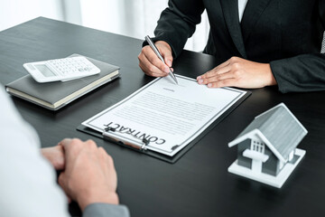 Real estate agent working sign agreement document contract for home loan insurance approving purchases for client with house model and key on table