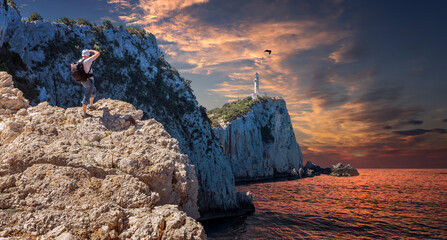 Beaotiful View of the Lighthouse on the cliff. Summer seascape of Cape Lefkatas with old lighthouseduring sunset. Wonderful picturesque vivid landscape over the Ionian Sea. Lefkada island. Greece.