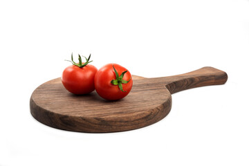 Two fresh red juicy tomatoes placed on a wooden board
