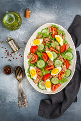 Delicious salad with tuna, fresh vegetables (lettuce, tomatoes, cucumbers), eggs with a dressing of olive oil, lemon juice and freshly ground pepper. Mediterranean cuisine. Nicoise. Selective Focus