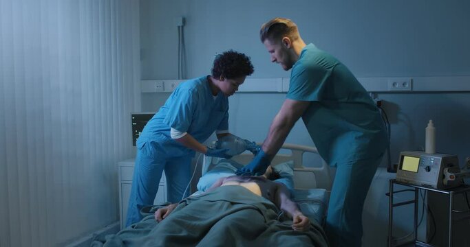 Doctors putting an oxygen mask on patient and doing cardiac massage in hospital.