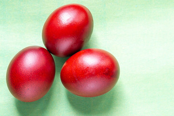 three red Easter eggs cooked in onion husks on a green background. Holy Holiday of Bright Easter 2021 concept