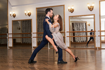 couple practicing dancing tango in a spacious empty hall