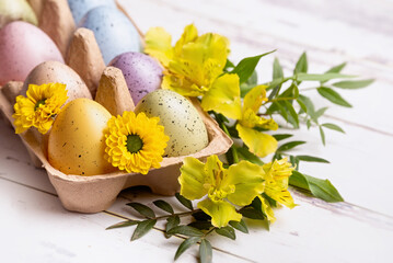 Multicolored Easter eggs in a tray and flowers