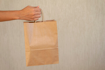 woman delivering cardboard shopping bag with space for text.