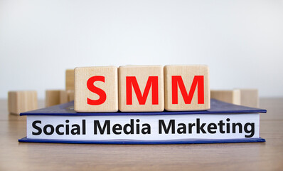 SMM, social media marketing symbol. Wooden cubes on book with word 'SMM - social media marketing' on beautiful white background, copy space. Business, SMM - social media marketing concept.
