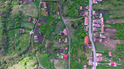 Fototapeta premium Aerial top view of a countryside village in Romania. Rural countryside landscape were the hamlet is located on a hilly region populated by trees.