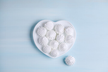Meringue cake on a white porcelain plate in the shape of a heart. Photos of desserts for proper nutrition. Valentine's Day food and decor.