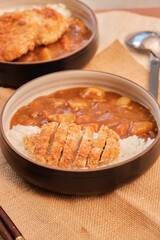 Top view Japanese curry rice topping with fried pork and vegetables in white and black plate with chopsticks. Curry rice Japanese food.