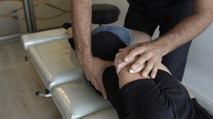 Fototapeta na wymiar Hands of chiropractor working on female patient's back who lies facing sideways on stretcher. Osteopath appointment, treatment concepts