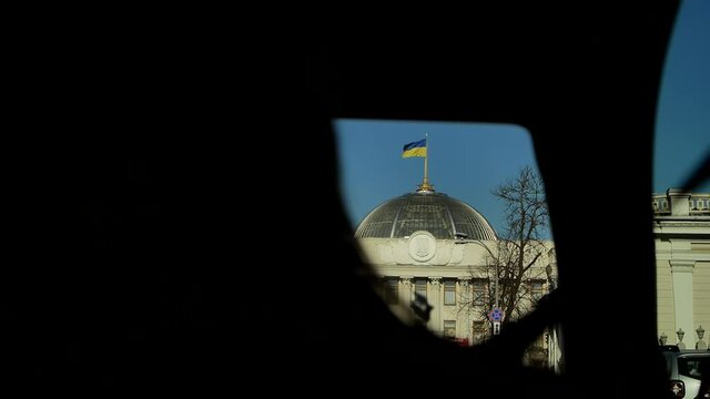 Video shooting from a car while traveling in Kiev and Ukraine. The fluttering Ukrainian flag over the parliament building in the center of Kiev. Verkhovna Rada of Ukraine. The house of government.