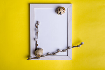 Pussy willow branches with  quail eggs and frame  on yellow background. Spring and Easter holiday concept. Top view