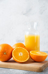 Glass pitcher of juice with sliced orange fruit on a wooden board