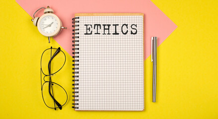 ETHICS Notice on the notepad with pen, glasses and alarm clock