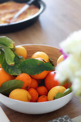 Bowl of fruit and flowers on a dining room table. Selective focus.