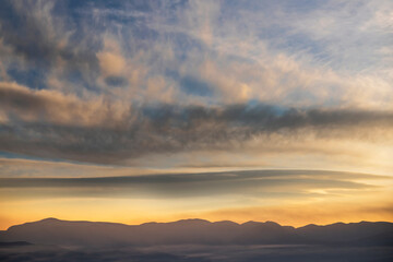 Beautiful panoramic view on the mountains silhouette on the sunset with bright clouds.