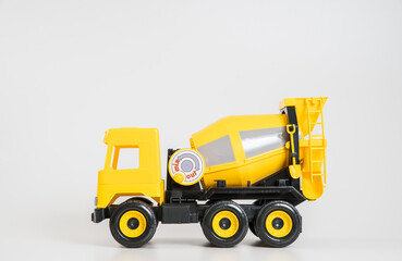 Plastic car. Toy model isolated on a white background. Yellow truck for the transport of building concrete.