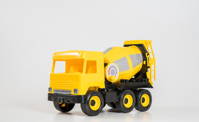 Fototapeta na wymiar Plastic car. Toy model isolated on a white background. Yellow truck for the transport of building concrete.