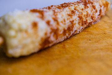 Mexican corn with chili powder and grated cheese on a wooden surface