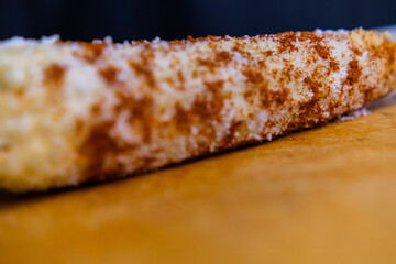 Mexican corn with chili powder and grated cheese on a wooden surface