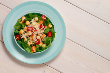 Caesar salad with chiken , on a white wooden table, top view, no people,