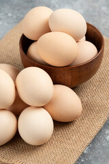 Wooden bowl of organic raw eggs on marble surface