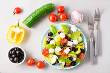 Fresh homemade greek salad with basil leaves on a plate and ingredients for cooking on the table. Domestic life. Top view