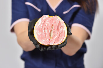 Beautician shows a grapefruit with wax for depilation similar to female genitals, the concept of female intimate depilation and femininity