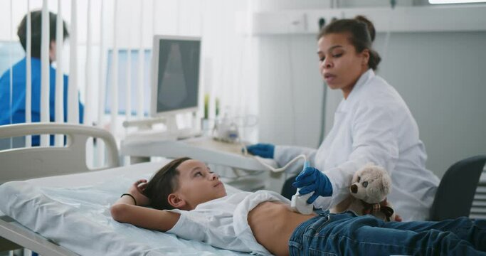 Doctor examining little patient belly with ultrasound at hospital