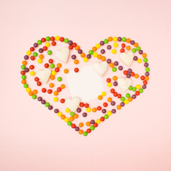 Love background flat lay concept. Copy space in heart full of colorful balls on pink background.