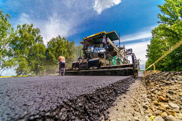 Road repair, compactor lays asphalt. Heavy special machines. Asphalt paver in operation. View from...