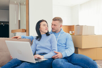 A couple in love with the newlyweds, moved to a new apartment, and use a laptop to choose new furniture for the apartment. make joint purchases online together