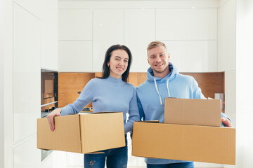 Young couple, man and woman look at the camera and hold boxes with things in their hands, moving to...
