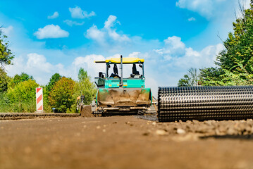 Fototapeta na wymiar Road roller at a road construction site. New road construction. Suuny day. Ground road to be layed with asphalt.