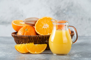 A wicker box full of juicy orange fruits on stone background