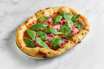 Delicious pizza with roast beef, sun-dried tomatoes, pickled onions, cheese and spinach on a white plate on a white marble background