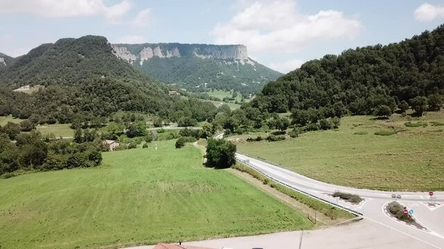 Aerial Forward: Road Amidst Trees Leading To Mountain Against Sky