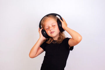 A cute girl listens to music with her headphones closed.