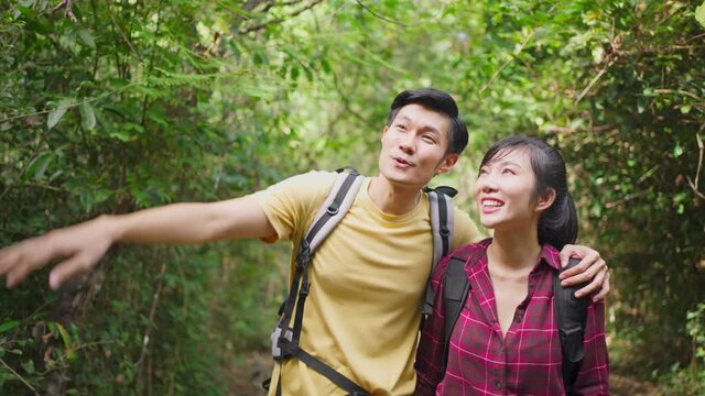 Asian young backpacker couple travel through a forest in the summer.