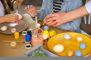 Little boy painting wooden eggs for Easter decoration