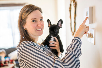 woman set the thermostat at house with french bulldog