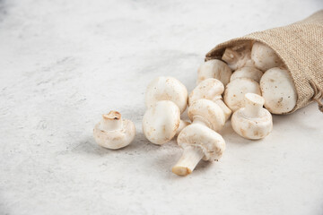White mushrooms inside rustic baskets on marble background