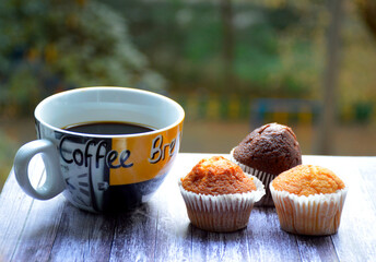 a cup of coffee and three muffins for breakfast, on the background of nature