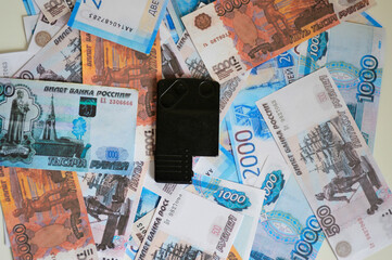 the electronic car key lies against the background of Russian money of various denominations