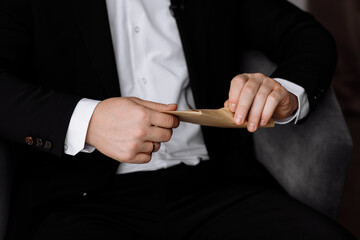 the groom holds an envelope with a letter from the bride. man is reading and sitting in the chair near the window. A letter for the groom. declaration of love.
