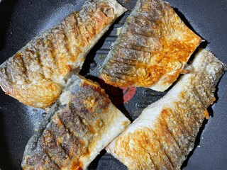 fish is grilled in a skillet. fried mullet slices. seafood food.