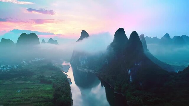 In the morning, drone flying upward over the stunning karst landforms surrounded by clouds in Yangshuo, Guangxi
