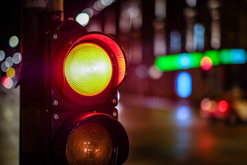 Red light on pedestrian traffic light in the street junction in the city with beautiful bokeh lights in the night. Defocused