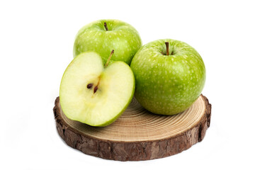 Whole and sliced green apples on wood piece on white background