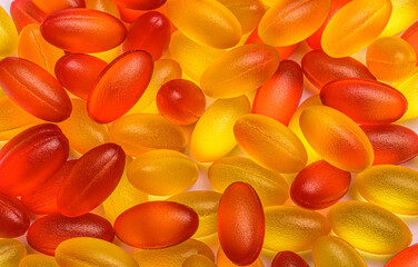 Close up of red and yellow pills. Omega3 and Vitamin D3. A scattering of tablets. Medicine capsules.